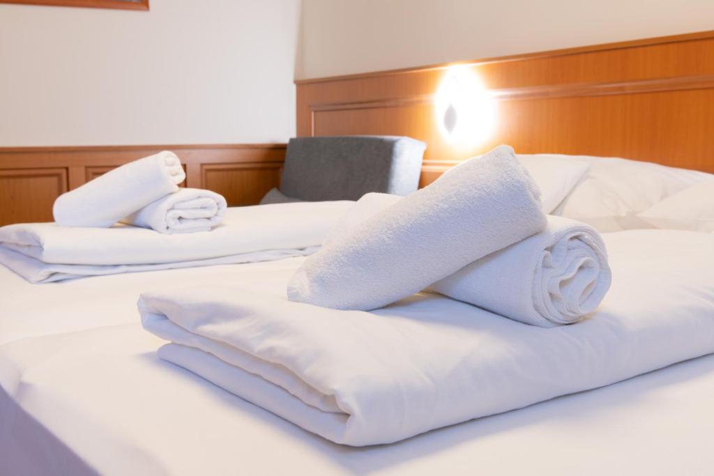 three white towels on top of a bed at Szinbád Hotel in Pécs