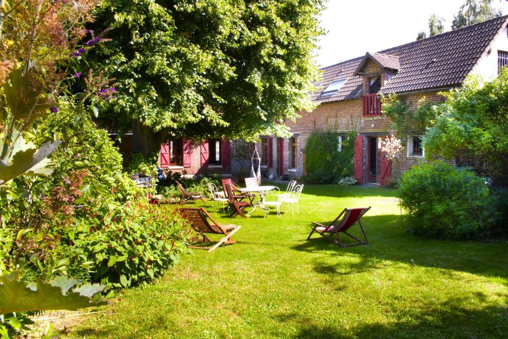 un patio con sillas, una mesa y una casa en La FERME DU TILLEUL Chambres d hôtes tout conforts - familiale - entre amis - pro en Conchy-les-Pots