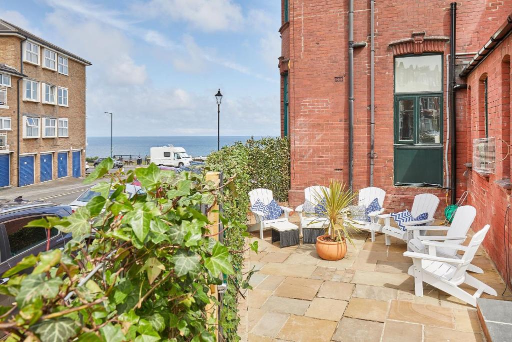 a patio with white chairs on a brick building at Sandside Beachfront Cottage Perfectly Saltburn in Saltburn-by-the-Sea