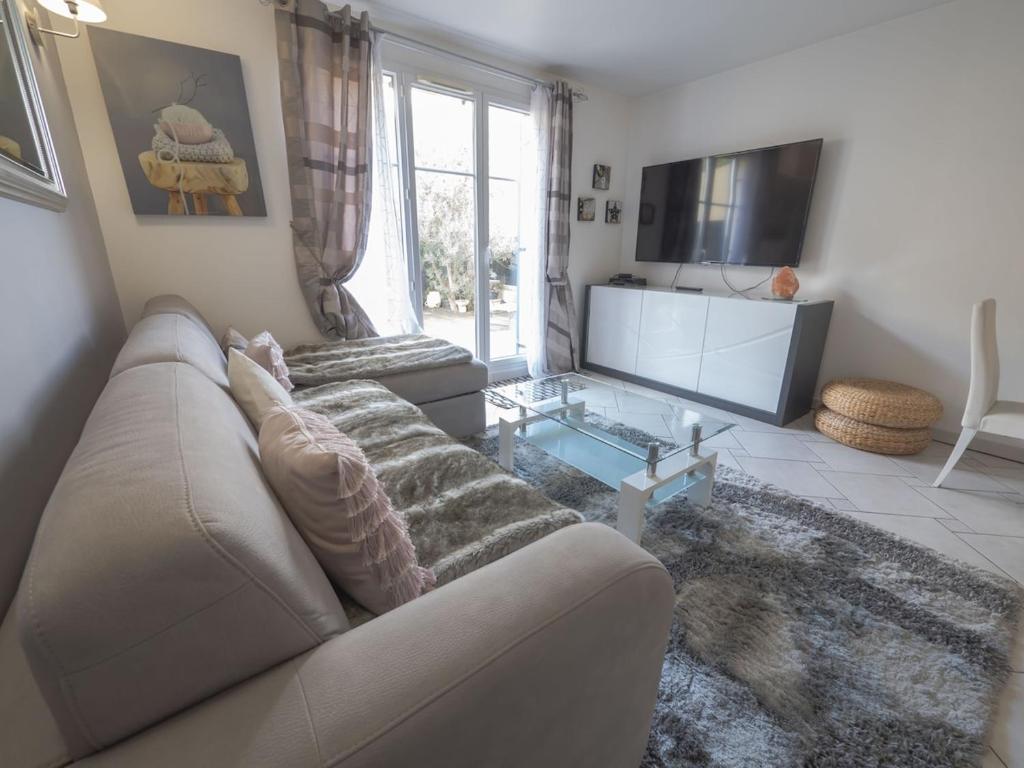 ein Wohnzimmer mit einem Sofa und einem TV in der Unterkunft TEA&CHILL- Les Bluets - house with 2 terraces in Noisy-le-Sec
