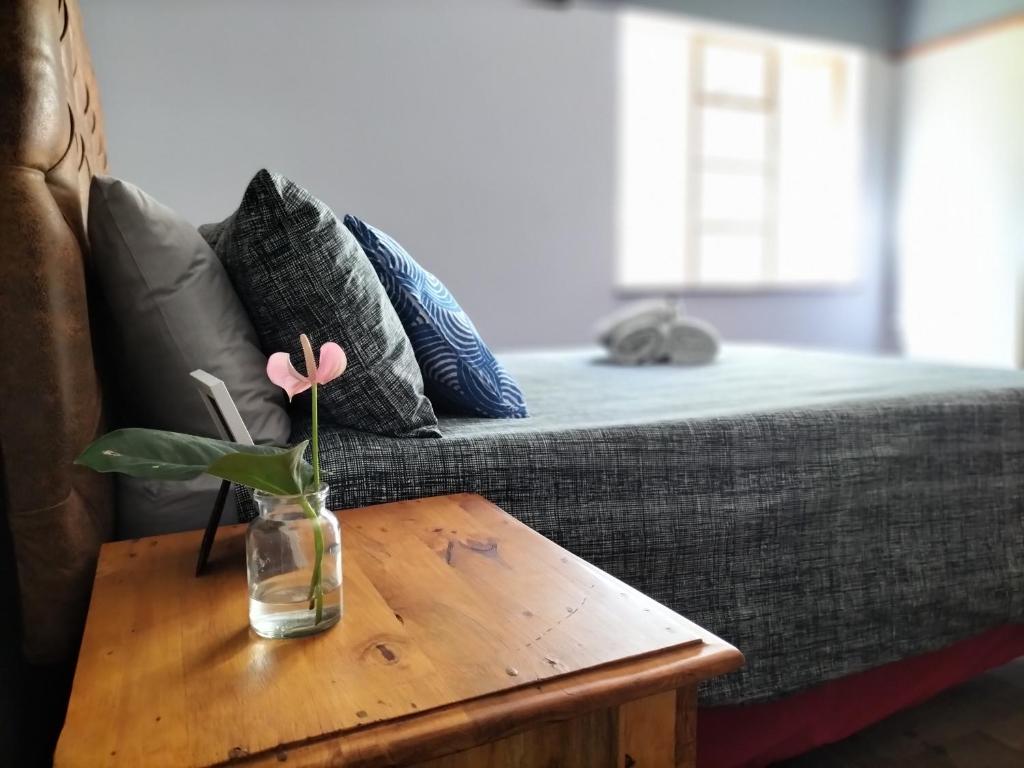 a glass vase with a flower on a table next to a couch at Fair Haven in Bloemfontein