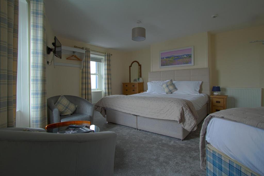 a bedroom with a bed and a chair and a couch at The Harbour Inn in Garlieston