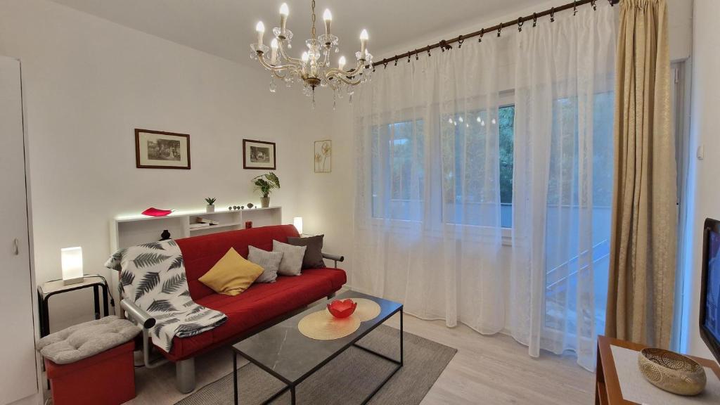 ein Wohnzimmer mit einem roten Sofa und einem Kronleuchter in der Unterkunft Apartments Godena in Rovinj