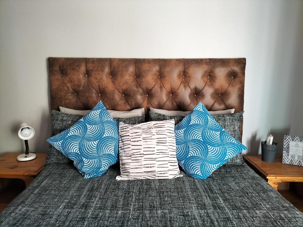 a bed with three blue and white pillows on it at Fair Haven in Bloemfontein