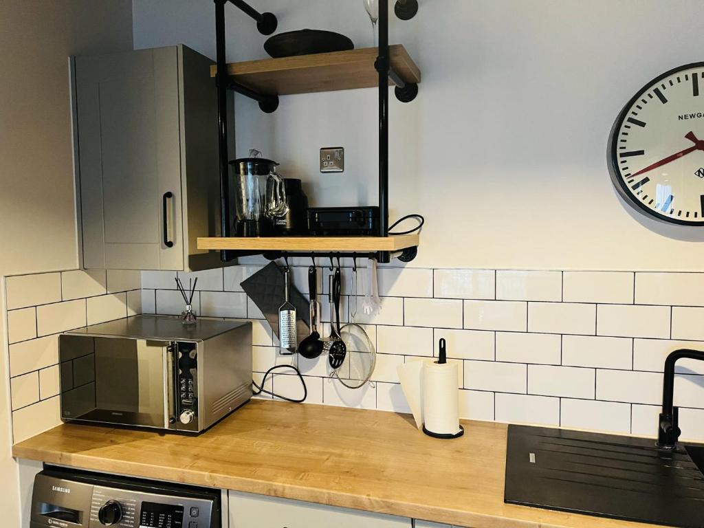 a kitchen with a microwave and a clock on the wall at Homely 2-Bed Apartment with stunning Views Wembley in London