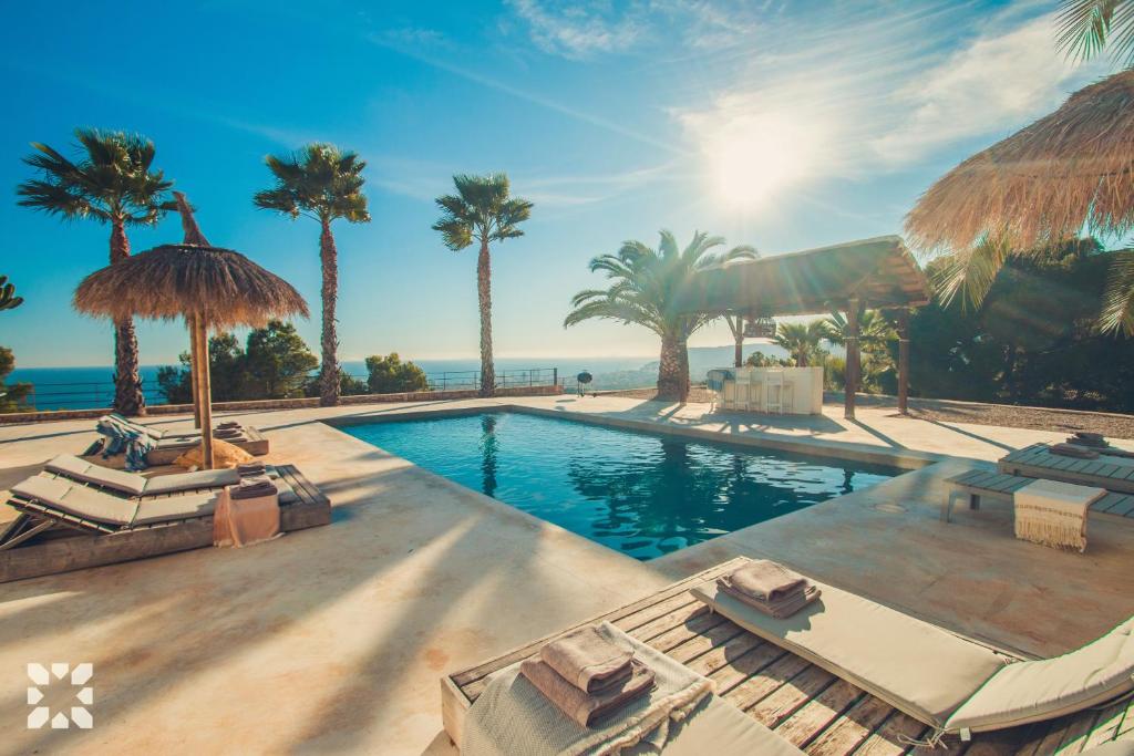 ein Resortpool mit Palmen und dem Meer in der Unterkunft Villa Rosina by Abahana Villas in Benissa