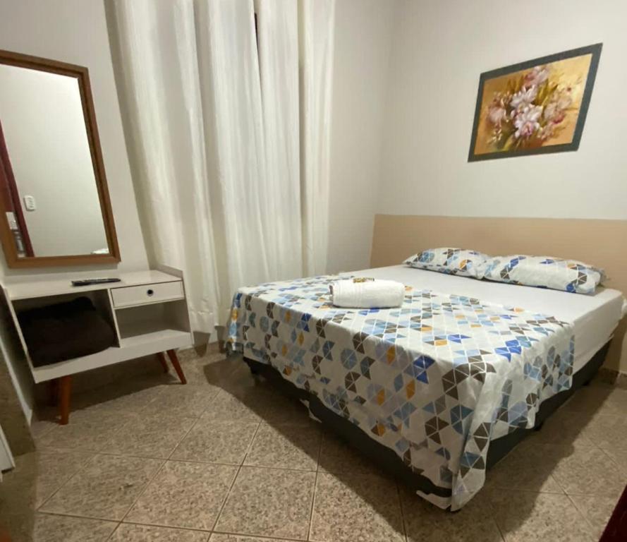 1 dormitorio con 1 cama y vestidor con espejo en Pousada e Hospedaria Regina, en Cachoeiro de Itapemirim