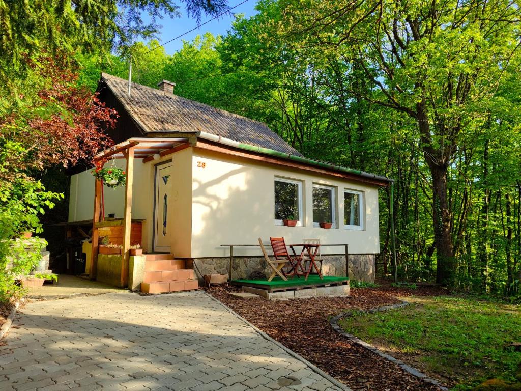 a small white tiny house with a porch and a patio at Csendes pihenés az erdő mellett - Madárfüttyös Vendégház in Pilisszentlászló
