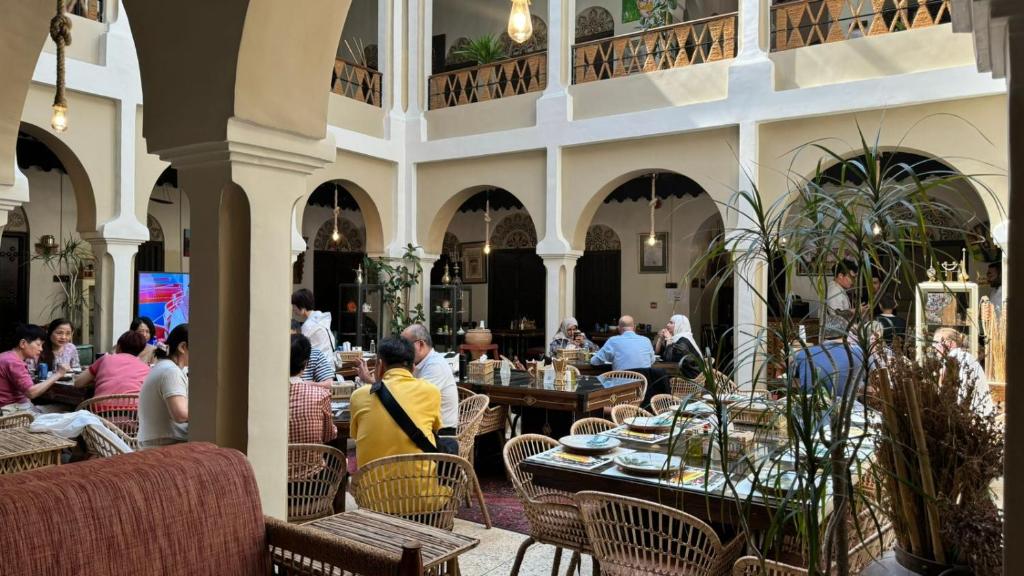 a group of people sitting at tables in a restaurant at Al Koot Heritage Hotel in Al Hofuf