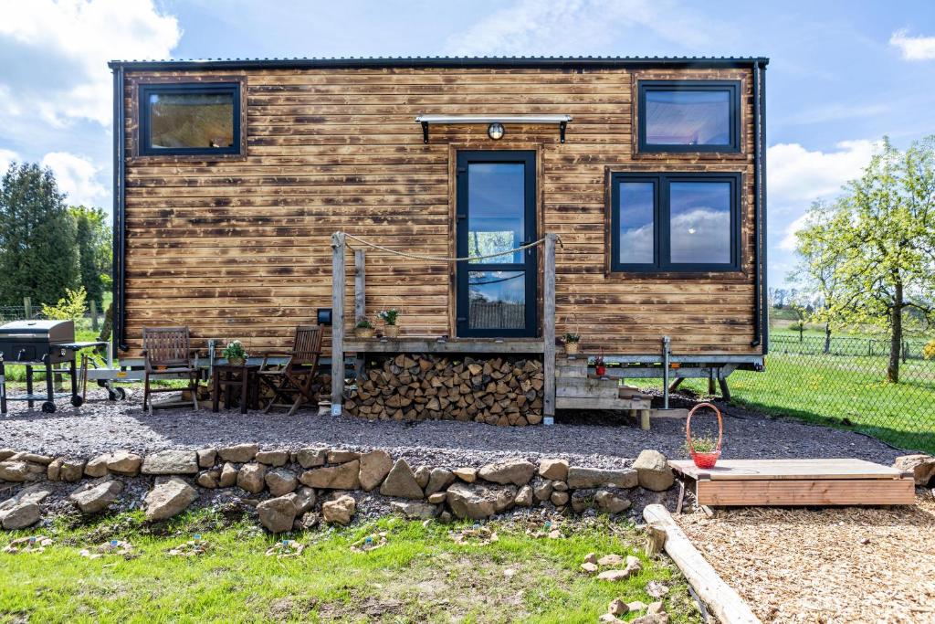 une cabane en rondins avec une table et des chaises dans une cour dans l'établissement Tiny House - Tinyinn No1, à Ulrichstein