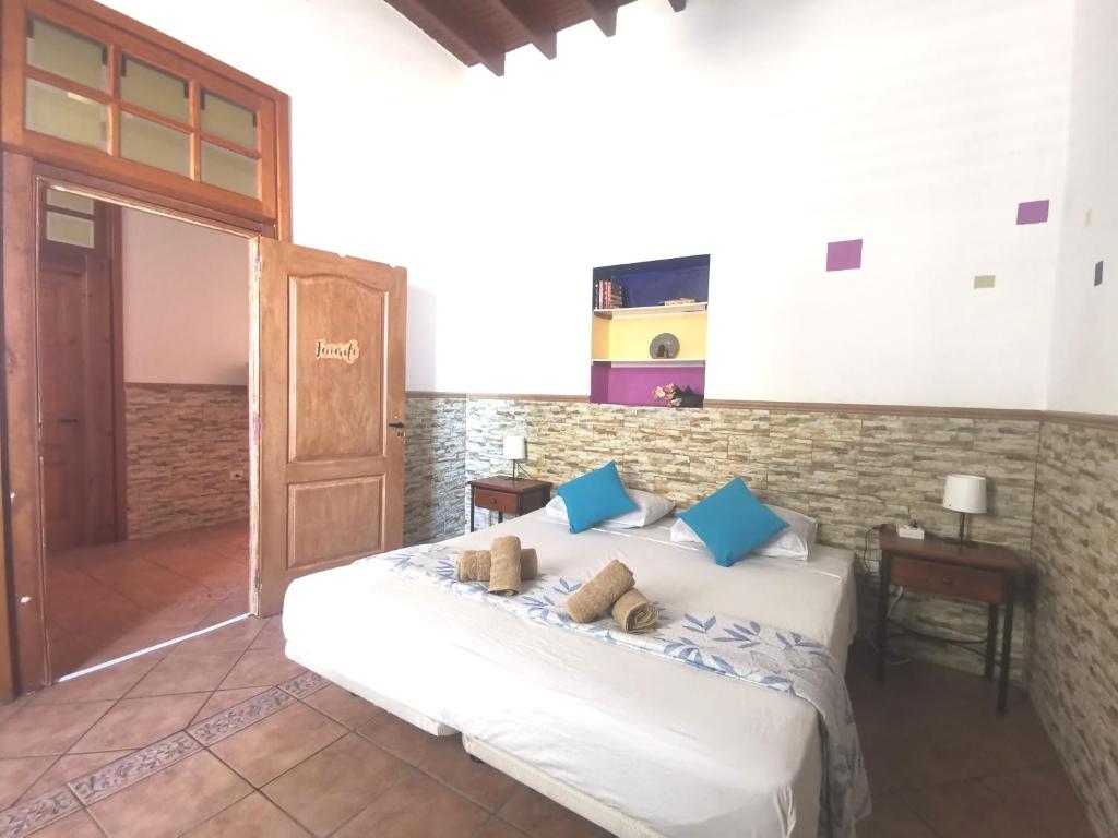ein Schlafzimmer mit einem weißen Bett mit blauen Kissen in der Unterkunft Eden House in Sardina