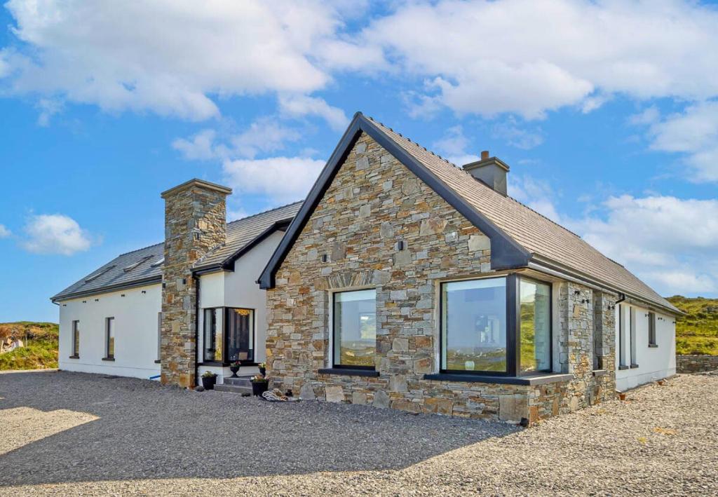 a stone house with large windows on a driveway at Sweet Garden, Mannin - Ballyconneely in Ballyconneely