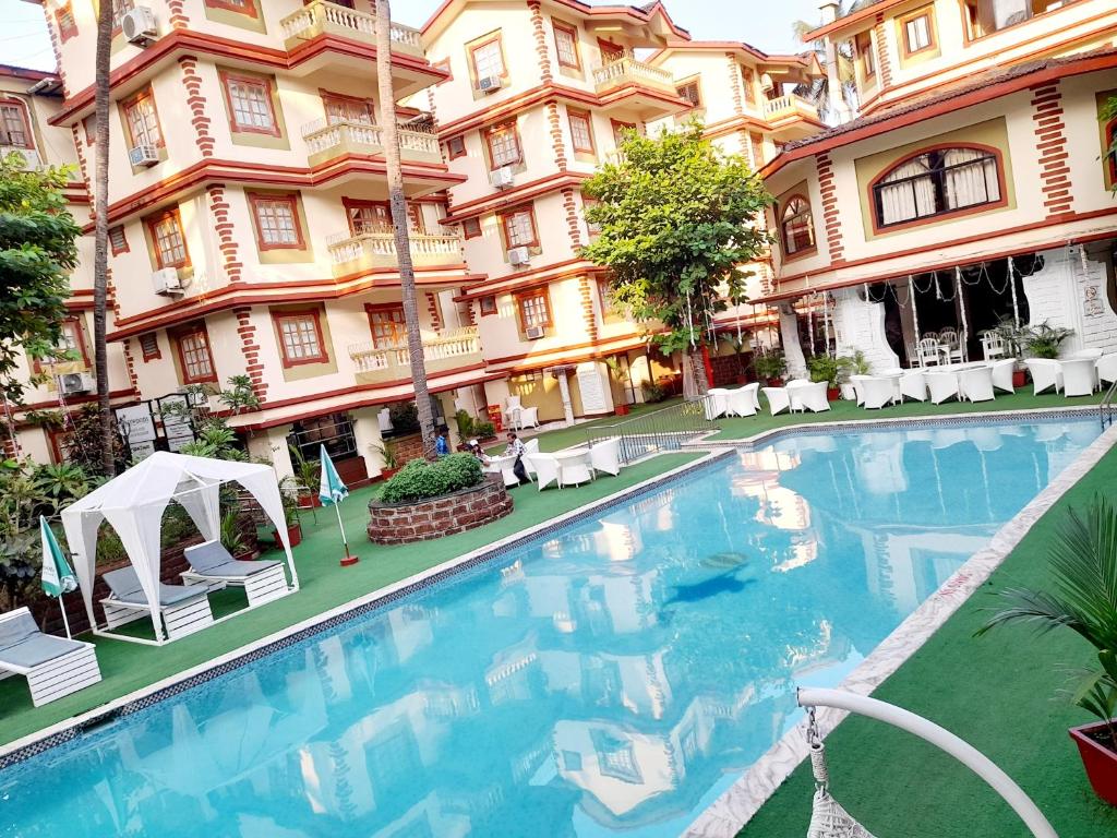 a large swimming pool in front of a building at Olive Garden Apartment in Candolim