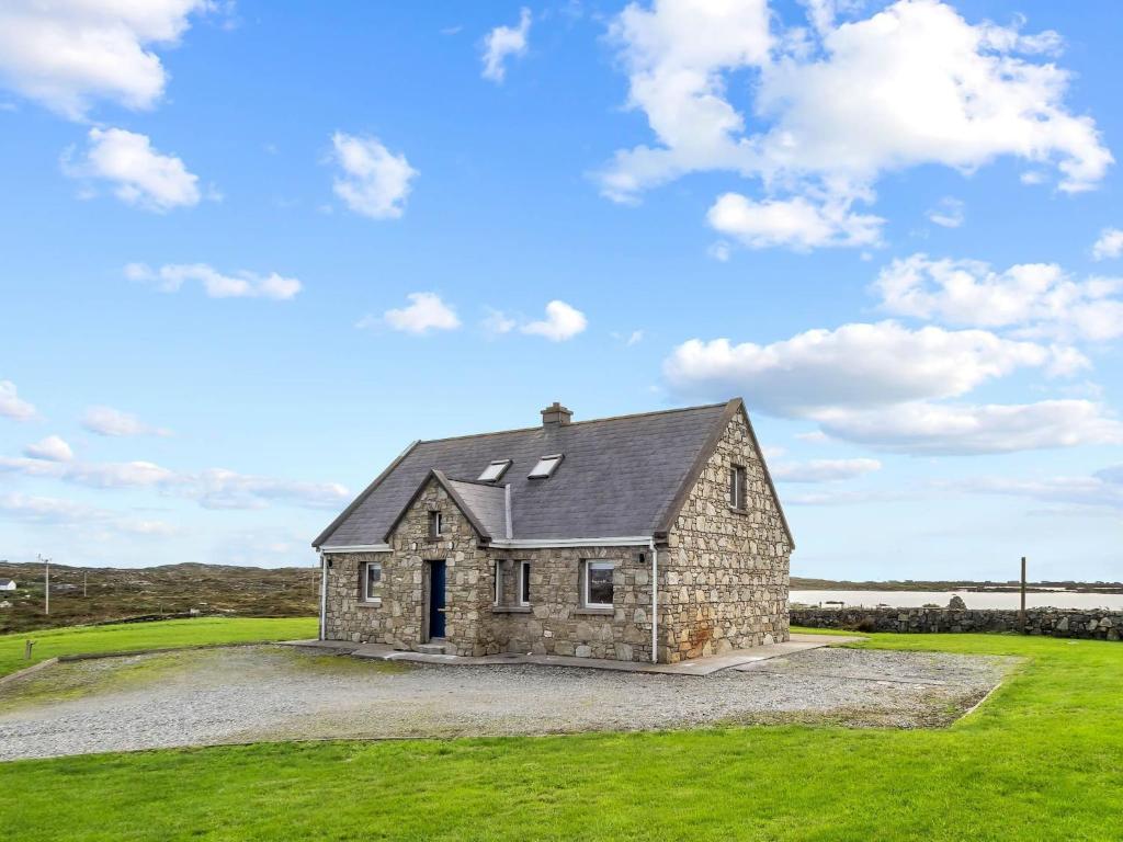 una casa de piedra en un gran campo de hierba en Lake House Mannin, Ballyconneely, en Ballyconneely