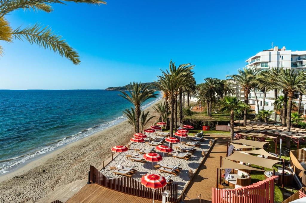 a beach with chairs and umbrellas and the ocean at Hotel Vibra Algarb in Playa d'en Bossa