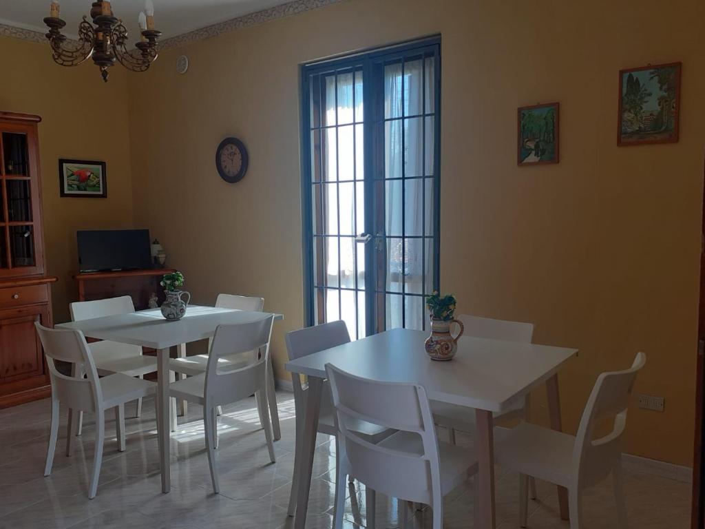 un comedor con 2 mesas blancas y sillas blancas en B&B Villa Rosina, en Satriano di Lucania