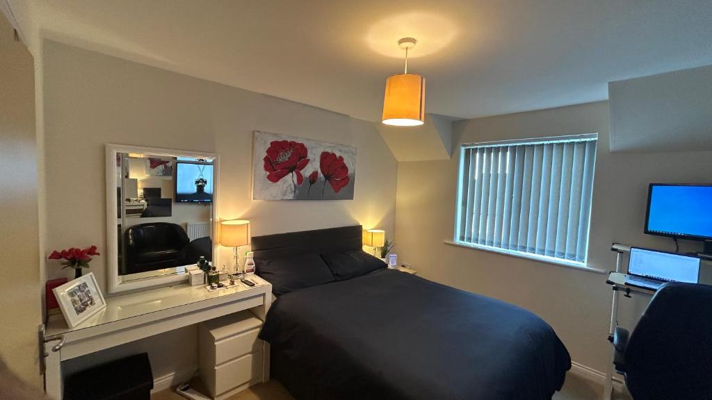 een slaapkamer met een bed, een bureau en een televisie bij Ensuite Double Bedroom in a 2 bed Spacious Apartment in Warrington