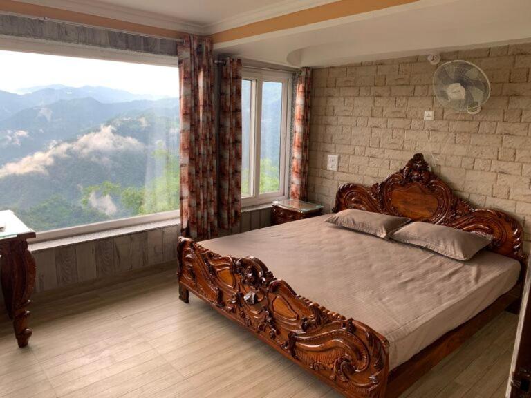 - une chambre avec un grand lit et une grande fenêtre dans l'établissement Swami Manjulanand Ashram, à Birbhaddar