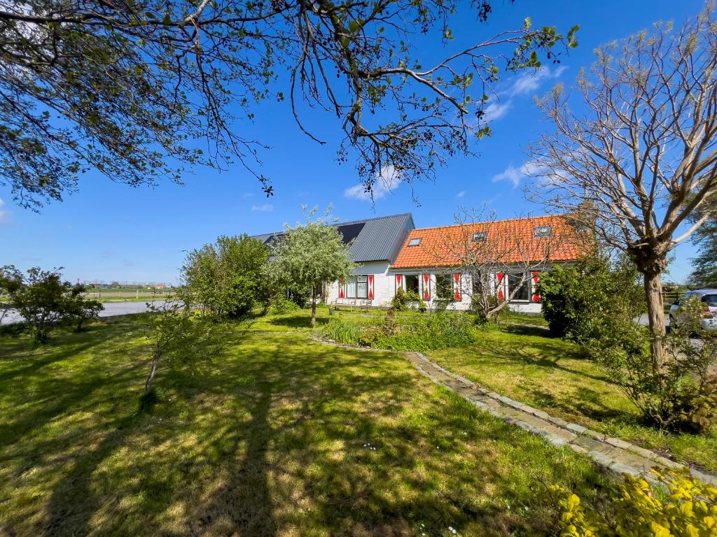 ein Haus mit einem orangenen Dach auf einem grünen Feld in der Unterkunft Het Zoete Pèèrd in Groede