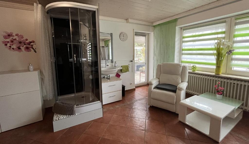 een badkamer met een douche en een stoel bij Allgäu Pension Ab in den Süden in Bernbeuren