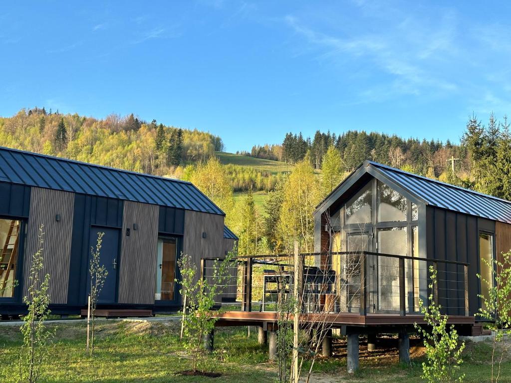 a black cabin with a deck and a house at Domki Piwniczna in Piwniczna-Zdrój