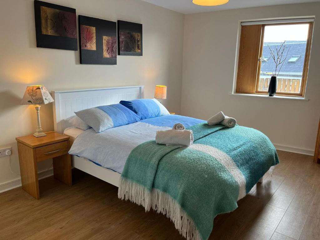 a bedroom with a bed with blue sheets and a window at 5 Courthouse Square Clifden in Clifden