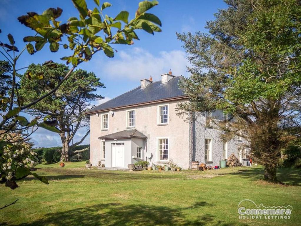 una gran casa blanca en un patio con árboles en Kill House, Kingstown en Clifden