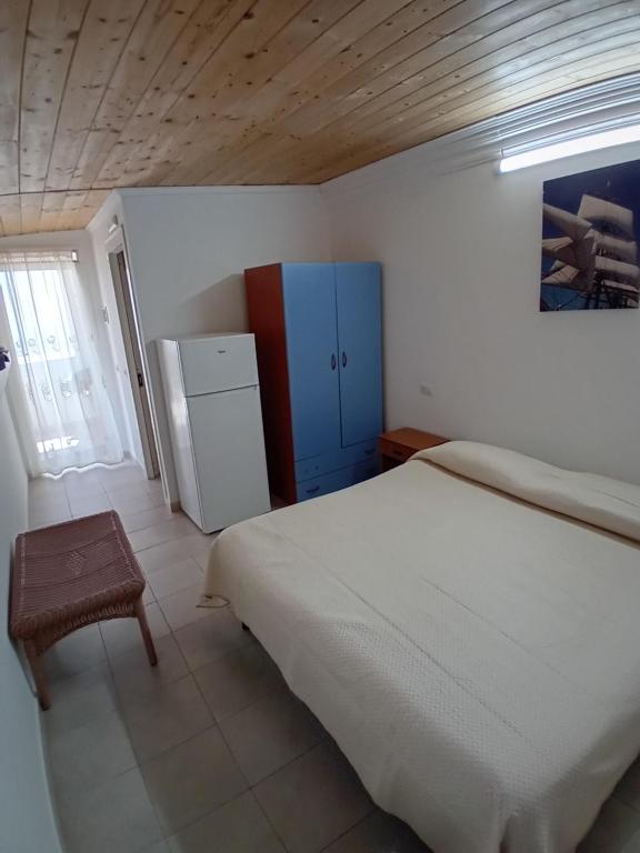 a bedroom with a white bed and a refrigerator at Case vacanze Leo & Cristina in Peschici