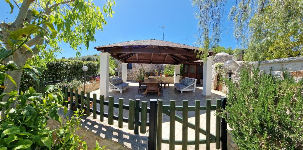 a patio with a wooden fence and an umbrella at Trullo Grande Noce in Cisternino