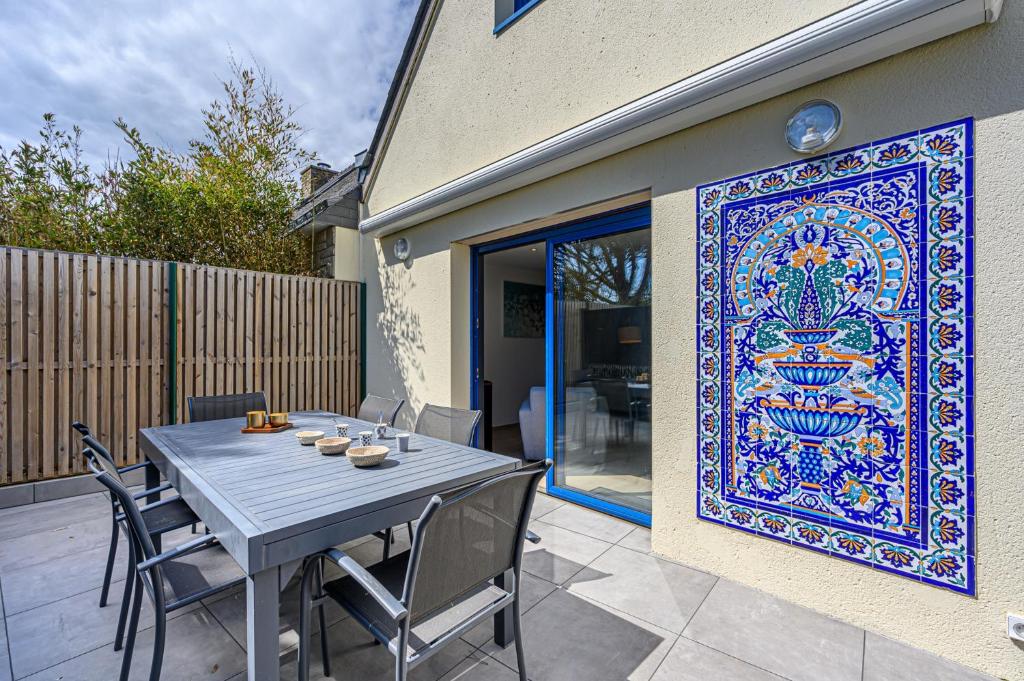 un patio avec une table et un grand tapis au mur dans l'établissement L'écrin du crouesty - Belle Maison pour 6, à Arzon