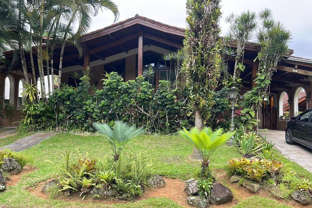 une maison avec des arbres et des plantes devant elle dans l'établissement Casa 30 m da praia,condomínio Tenório, à Ubatuba