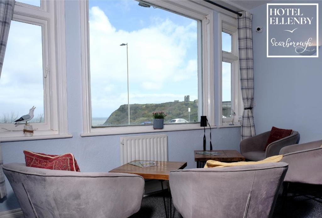 een woonkamer met een tafel, stoelen en ramen bij Hotel Ellenby in Scarborough