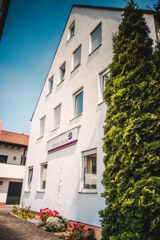 a tall white building with a tree next to it at Pension Krone in Schwäbisch Gmünd