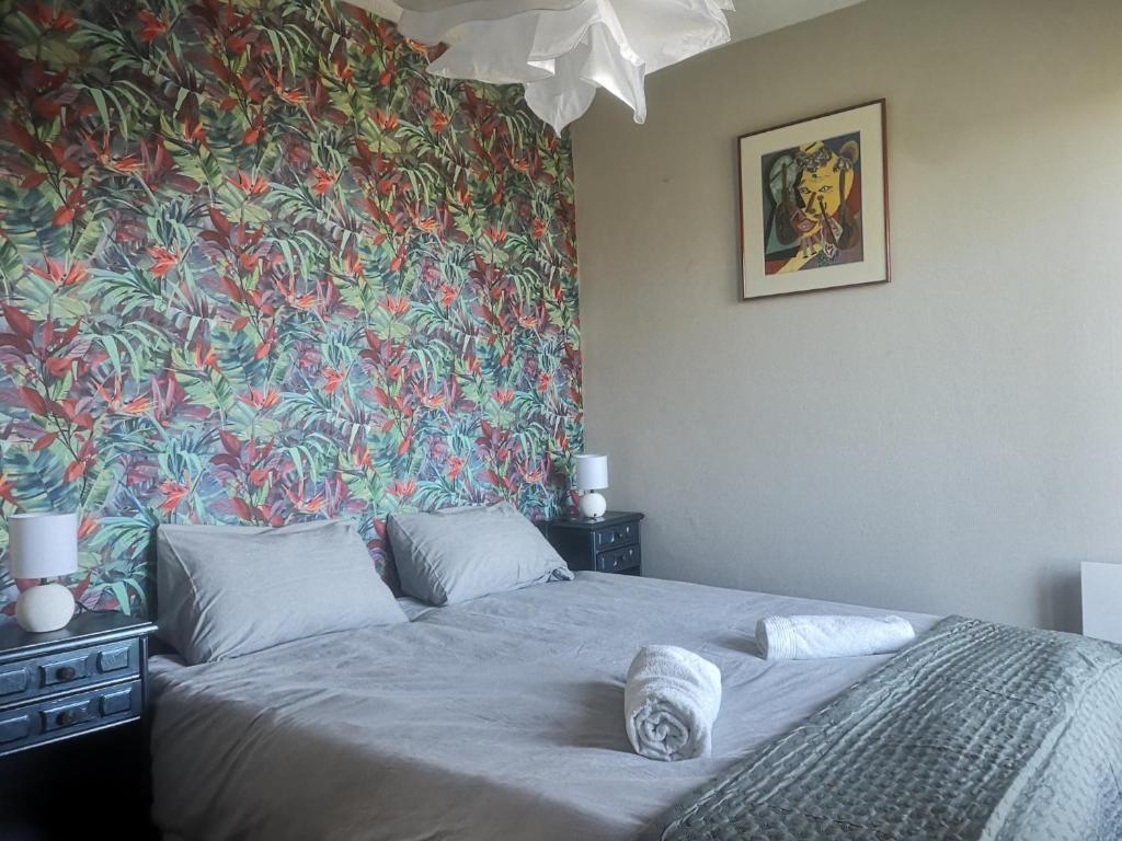 - une chambre avec un grand lit et du papier peint floral dans l'établissement Le pastel, à Albi