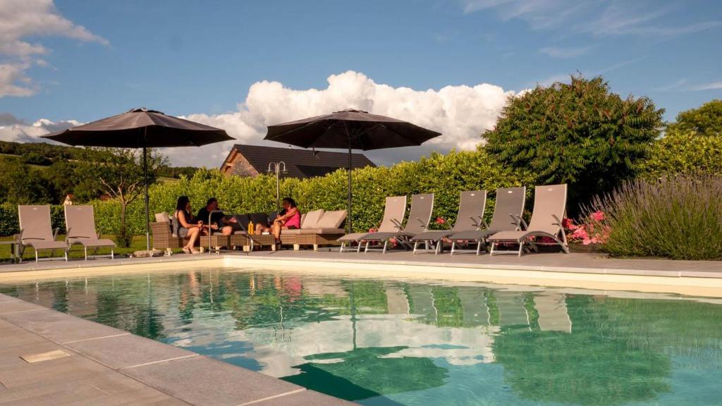 un grupo de personas sentadas en sillas junto a una piscina en Le Clos des 4 Saisons, en La Rochepot