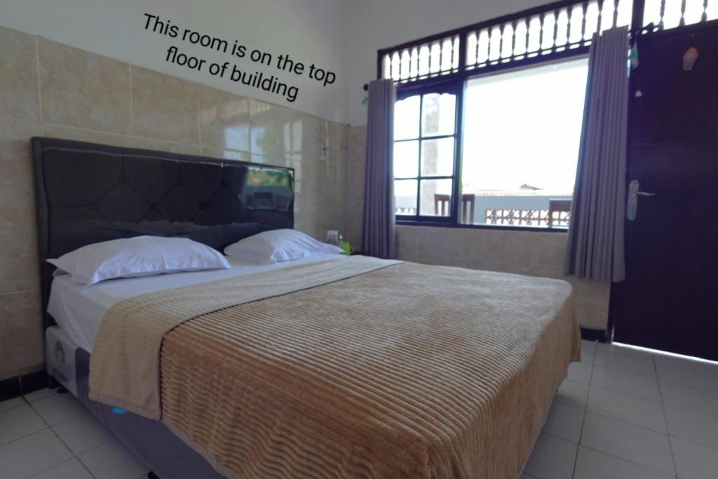 a bedroom with a bed with a large window at Pondok Dete Guesthouse in Sanur