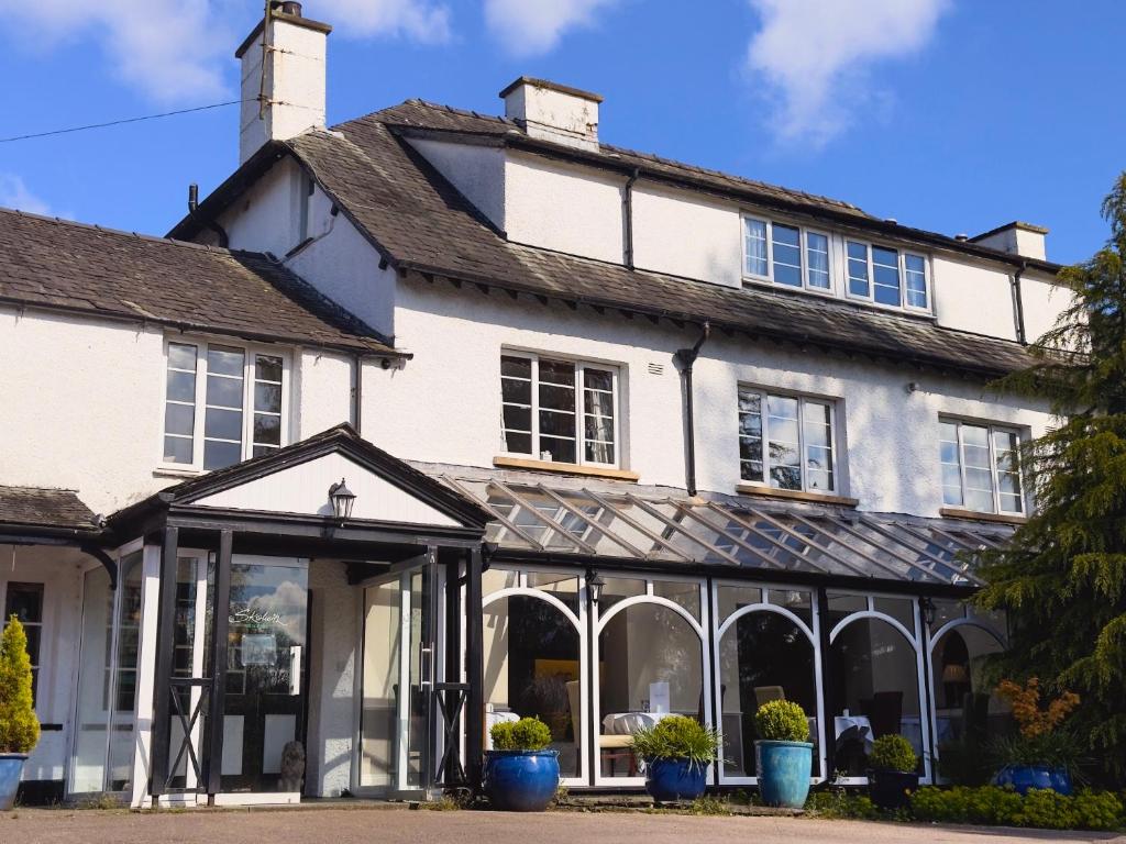 an old white house with windows and plants at Skelwith Bridge Hotel in Ambleside