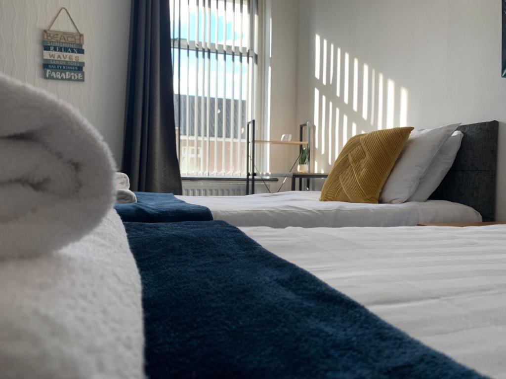 a bedroom with two beds with white sheets and a blue rug at Cheerful - 3 Bed - Serviced Accommodation - In Heart of Northumberland - Sleeps 6 in Bebside