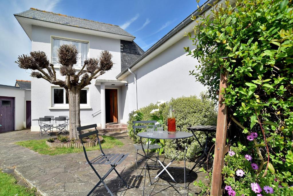 un patio avec une table et des chaises devant une maison dans l'établissement Douceur Malouine - Maison familiale avec jardin, à Saint-Malo