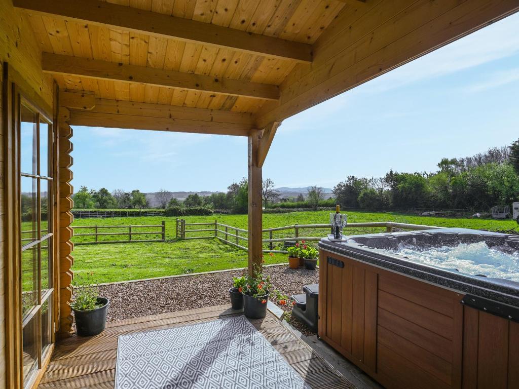 a large deck with a hot tub with a view of a field at Stable Lodge At Greenacre in Bromyard