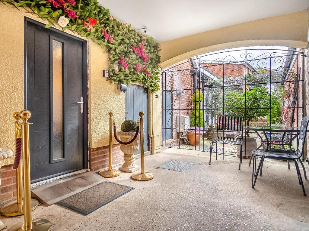 a porch with a black door and chairs and flowers at The Venetian in Horning