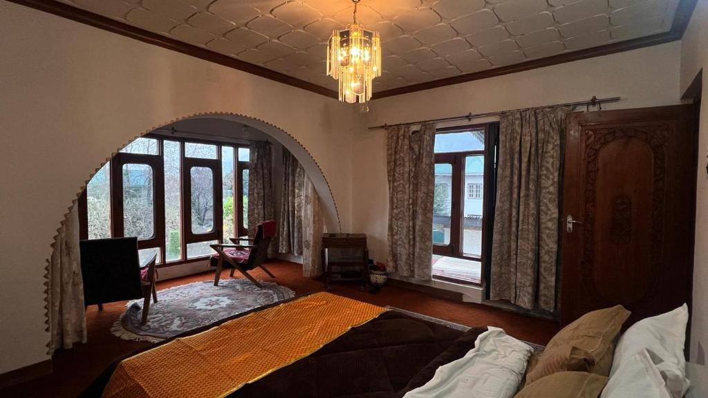 a bedroom with a bed and windows and a chandelier at Abshar Heritage Villa in Srinagar