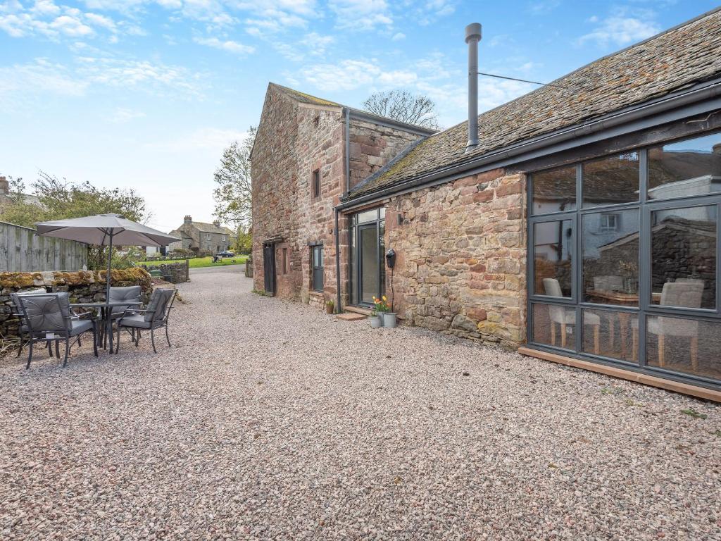 a patio with tables and chairs outside of a building at Cattle Cake Cottage in Askham