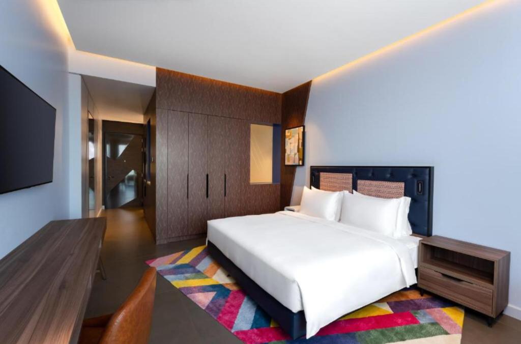 a bedroom with a large white bed and a television at Hyatt Centric Jumeirah - King Room Sea View - UAE in Dubai