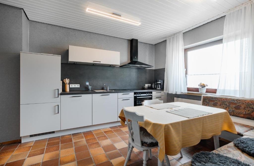 a kitchen with white cabinets and a table in a room at Ferienwohnung Wäller Mittagsonne in Westerburg