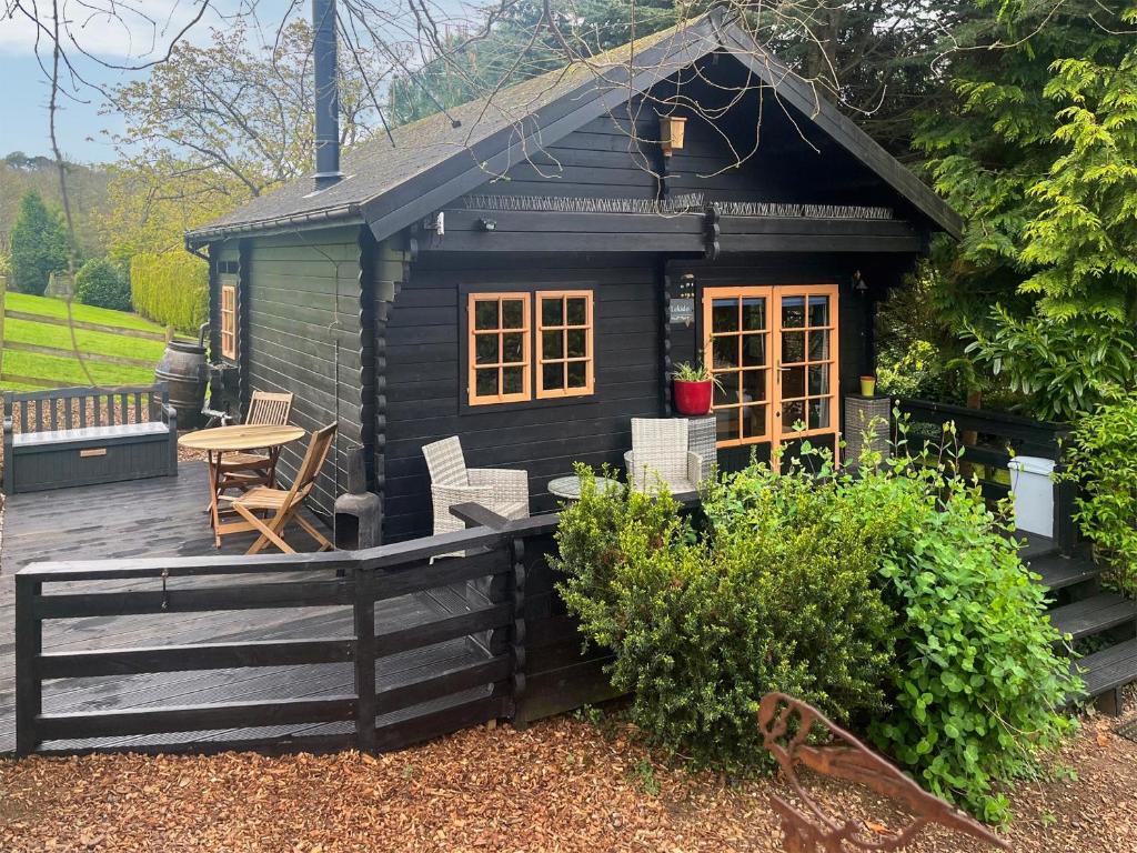 a black tiny house with a wooden deck at Lekido in Hernhill