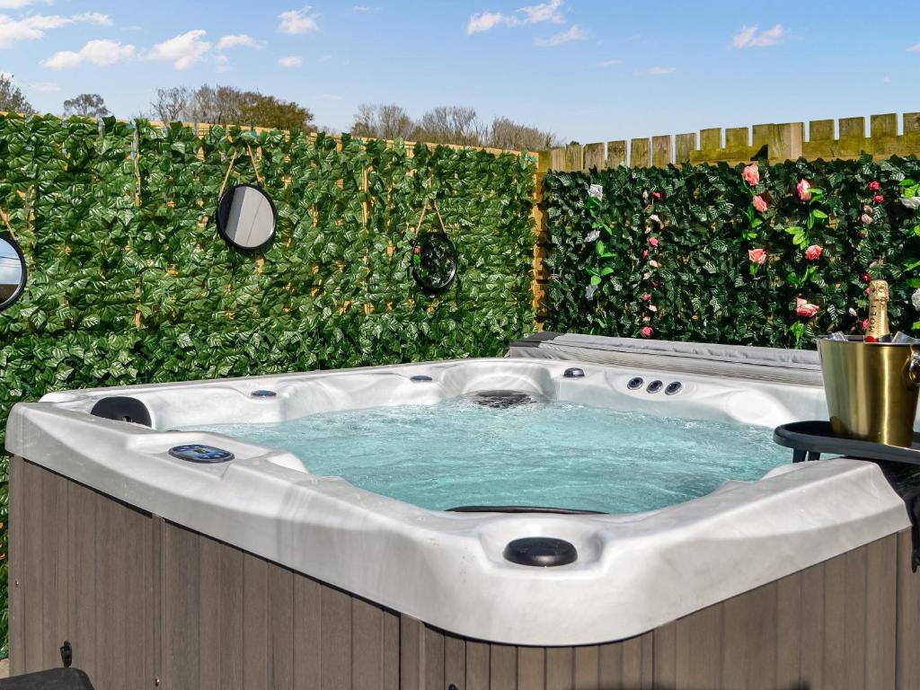 a hot tub in a garden with a hedge at Canda in Holywood