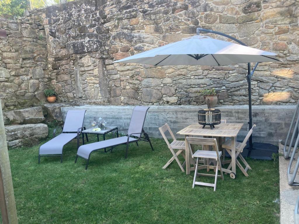 une table et des chaises avec un parasol sur l'herbe dans l'établissement Casa do Miguelo Costa da Morte, à La Corogne