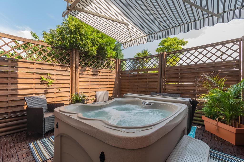 a jacuzzi tub on a patio with a fence at Flatbook - Sztutowo Lazurowy Dwór in Sztutowo