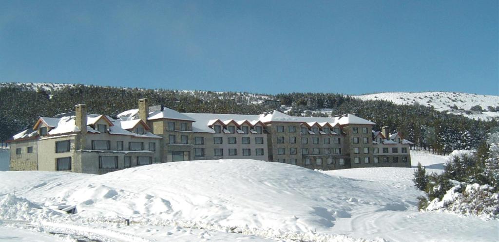 un grand bâtiment recouvert de neige devant une montagne dans l'établissement Loi Suites Chapelco Hotel, à San Martín de los Andes